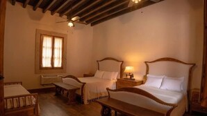 A traditional room with two wooden beds, a bench, and a window with curtains. - Hacienda Maria Trinidad (Valle de Guadalupe)