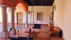 A spacious patio with a swing set, a leather sofa, and a wooden table. - Hacienda Maria Trinidad (Valle de Guadalupe)