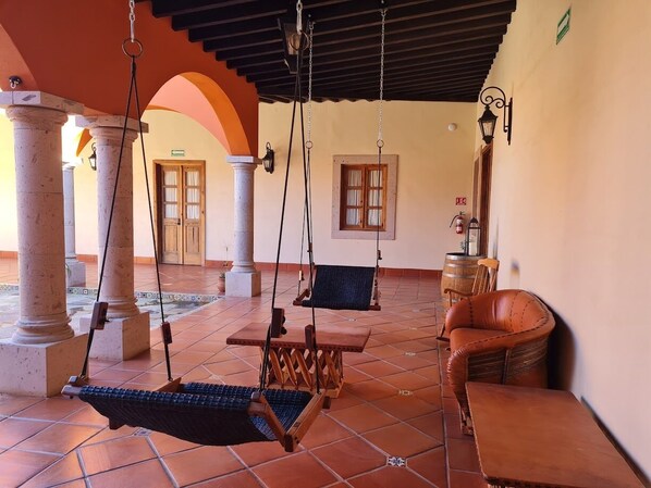 A spacious patio with a swing set, a leather sofa, and a wooden table. - Hacienda Maria Trinidad (Valle de Guadalupe)