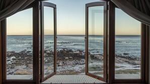 Una habitación con un gran ventanal que da a una playa de rocas.