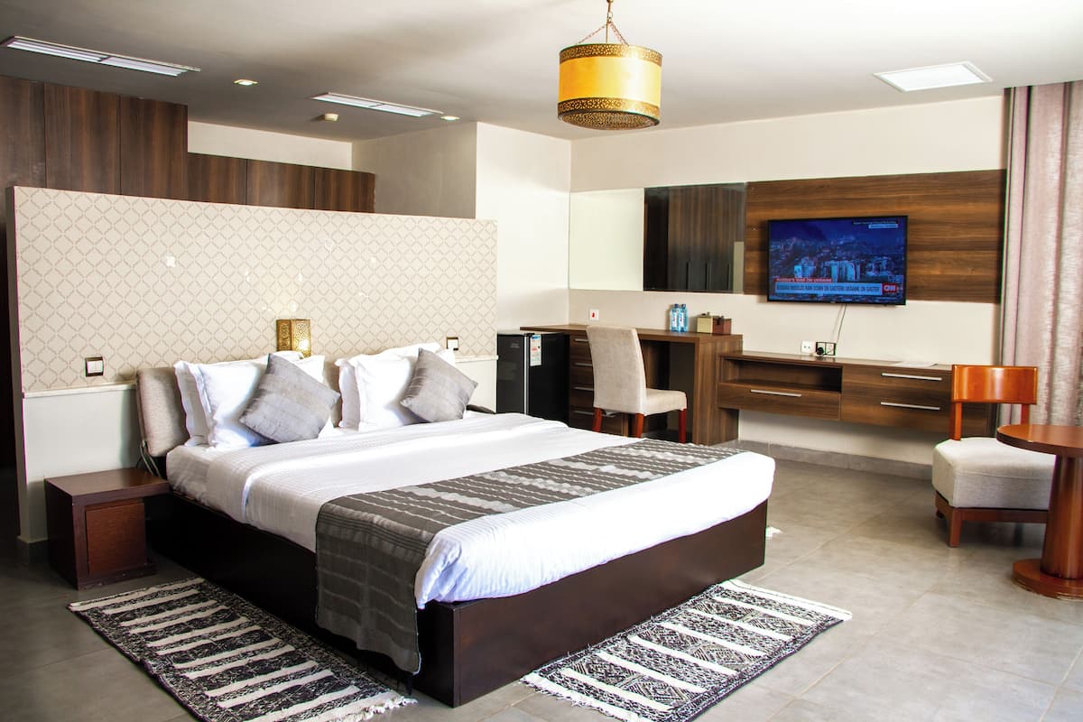 Una habitació d'hotel moderna amb un llit gran, una taula de treball, una televisió i un bany.