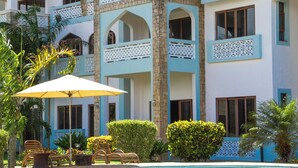 Un hotel de varios pisos con balcones, piscina y mobiliario exterior.