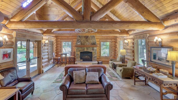 A log cabin interior with a fireplace, leather sofa, and wooden furniture. - Luxurious and Comfy Townhome w/ 2 Balconies & Patio w/ Mountain Views! (Keystone)