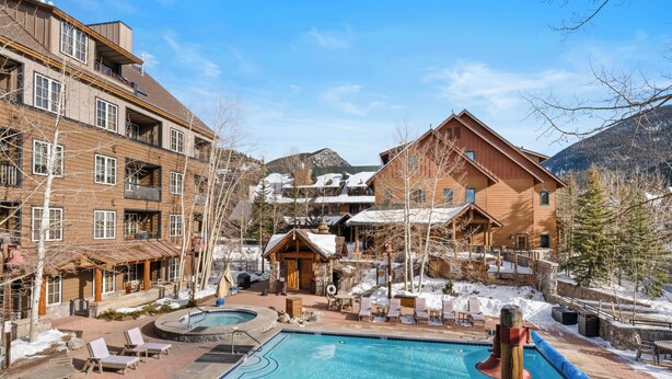 A resort with a swimming pool, outdoor seating, and a view of mountains.