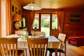 A wooden dining room with a table set for two, chairs, a lamp, and a view of the garden. - Find With Nr 509 Your Holiday Home in the Harz Mountains (Oberharz am Brocken)