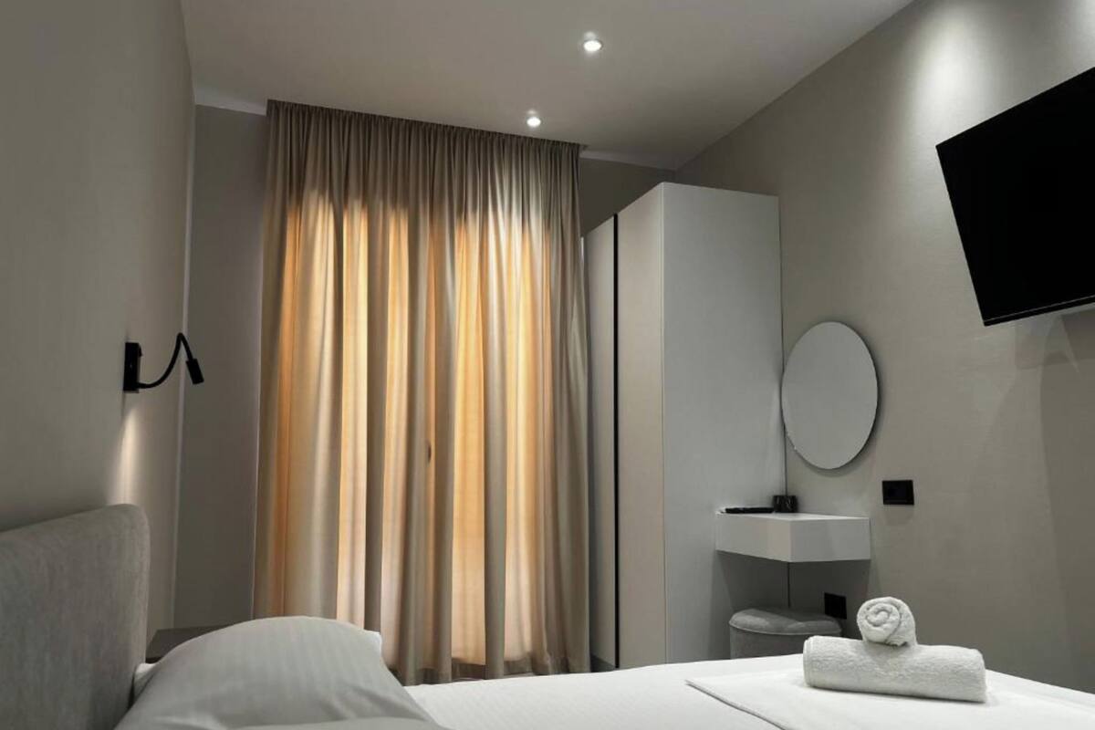 Une chambre d’hôtel moderne équipée d’un lit, d’une coiffeuse avec un miroir et d’un téléviseur à écran plat fixé au mur.