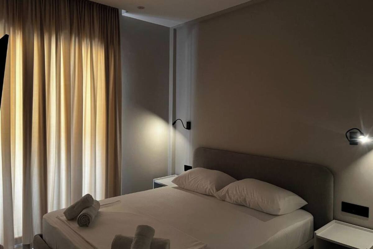 Une chambre d’hôtel moderne avec un grand lit, deux tables de chevet et une petite table d’appoint.