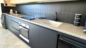 A modern kitchen with wooden cabinets, a black tiled backsplash, a stainless steel sink, and a dishwasher. - Peaceful retreat 6 km north of Coffs Harbour! (Korora)