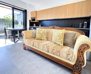 A sofa with intricate patterns, a dining table with chairs, and a kitchen area with wooden cabinets. - Peaceful retreat 6 km north of Coffs Harbour! (Korora)
