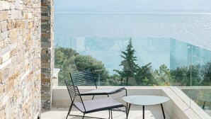 A balcony with a stone wall, a table, and two chairs. - Elia Cove Luxury Villas & Residences (Loutraki-Agioi Theodoroi)