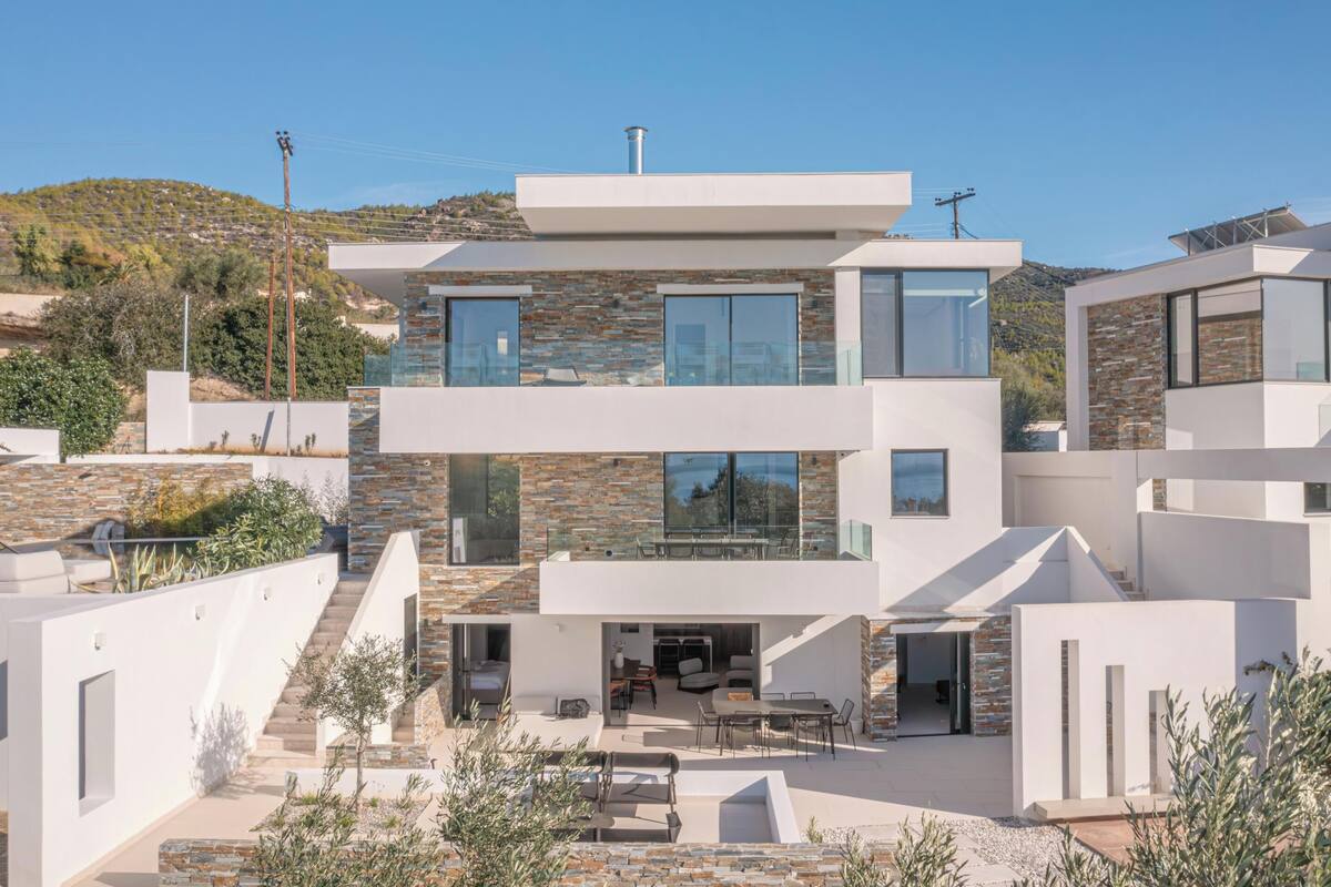 A modern two-story house with a patio area, large windows, and a stone facade.