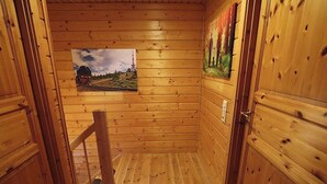 A wooden cabin interior with a wooden staircase, a framed picture on the wall, and a door. - The House to Stay for Holidays (Oberharz am Brocken)