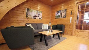 A cozy log cabin interior with a sofa, a coffee table, and two paintings on the walls. - The House to Stay for Holidays (Oberharz am Brocken)
