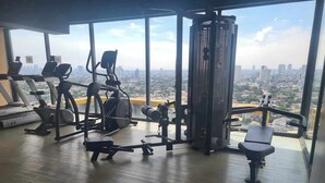 A gym with cardio machines, weightlifting equipment, and a city view.
