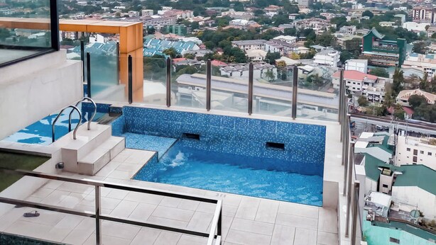 A rooftop pool with a city view, glass balustrades, and a modern architectural design.