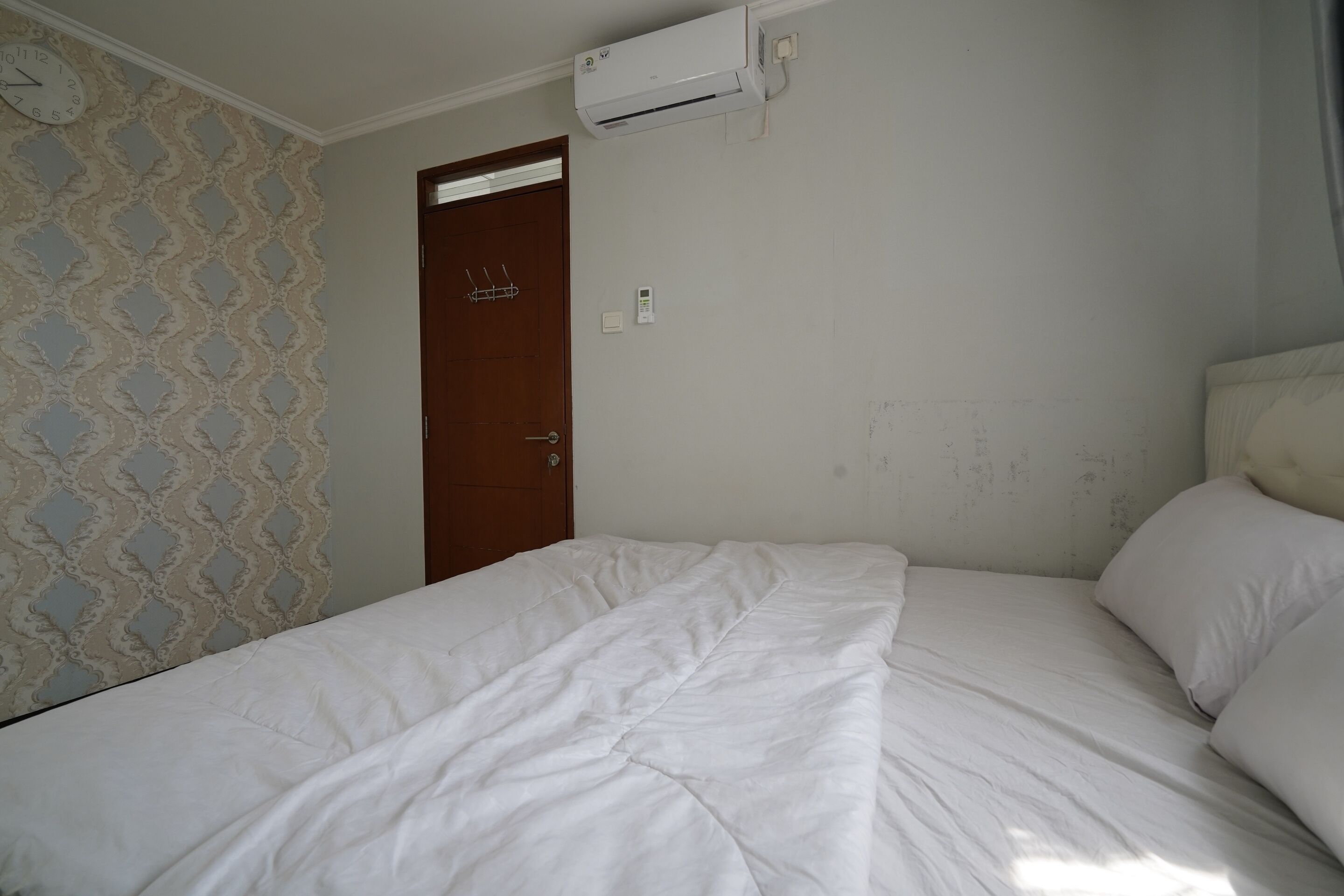 Une pièce comprenant un lit, une horloge murale et un appareil de climatisation.