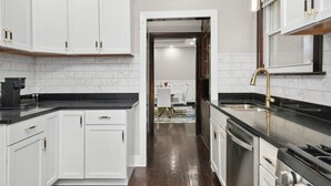 Una cocina moderna con armarios blancos, encimeras negras y electrodomésticos de acero inoxidable.