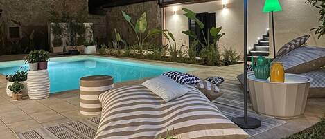 A poolside area with lounge chairs, a small pool, and potted plants.