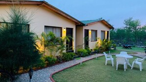 A two-story building with a garden and outdoor seating area. - The Jungle Hideout Jim Corbett (Ramnagar)
