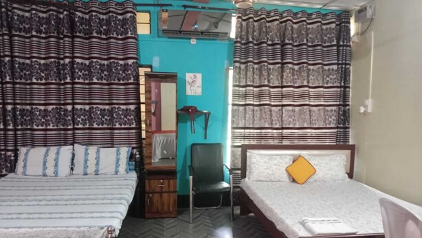 A room with two beds, a chair, and a desk. - Akshita Guest House By GRB (Palashbari)