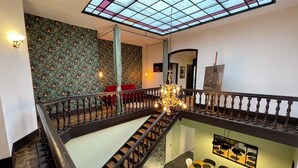 Ein mehrgeschossiges Interieur mit einer Treppe, einem Essbereich und einer Decke mit einem Buntglas-Design.
