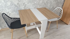 A small table with a wooden top and white legs, accompanied by a black and a white chair.