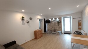 A modern living room with a wooden floor, a sofa, a coffee table, and a dining area with a table and chairs.