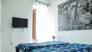 A bedroom with a bed, a television, a cityscape painting, and a window with curtains. - B&B Golfo incantato - Bisceglie (Bisceglie)