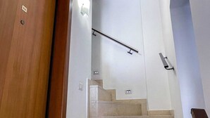 A staircase with a handrail, a wooden door, and a wall-mounted light fixture. - B&B Golfo incantato - Bisceglie (Bisceglie)