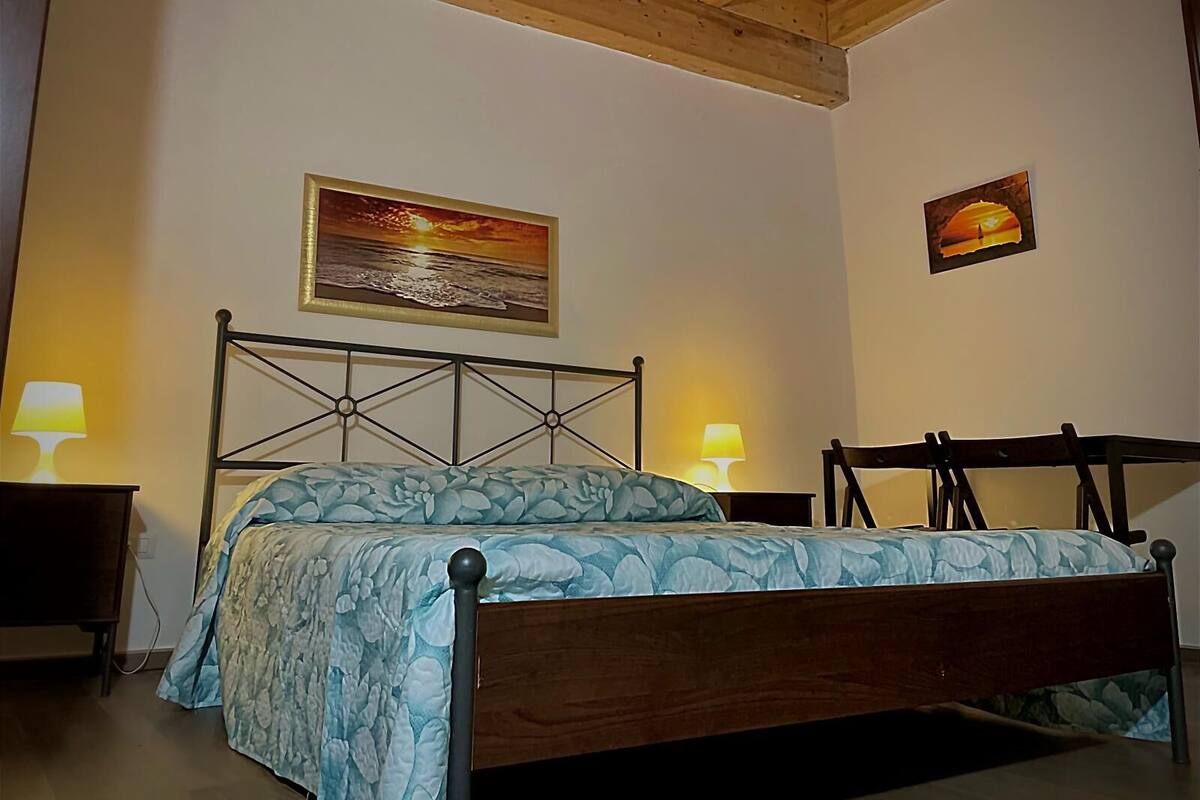 Un dormitorio con una cama, dos lámparas de noche y dos cuadros en la pared.