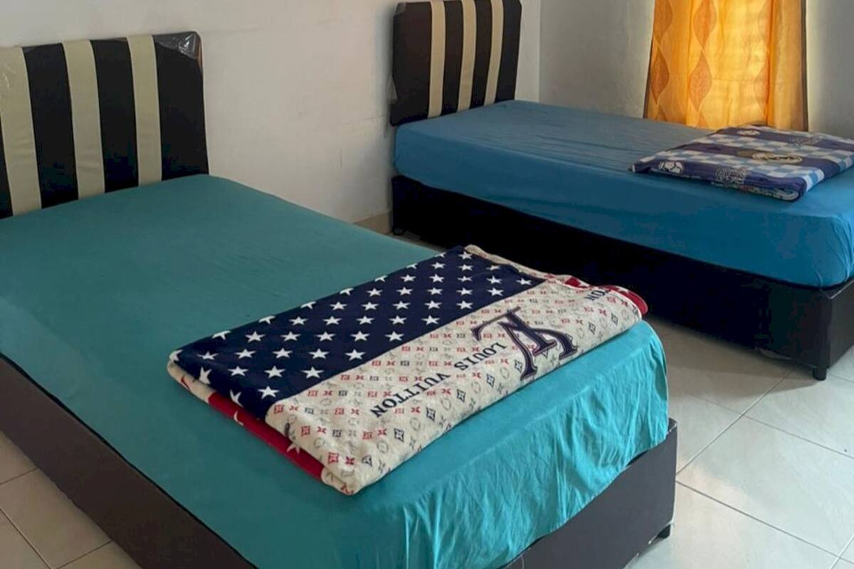A bedroom with two beds, each with a blue mattress and striped headboards.