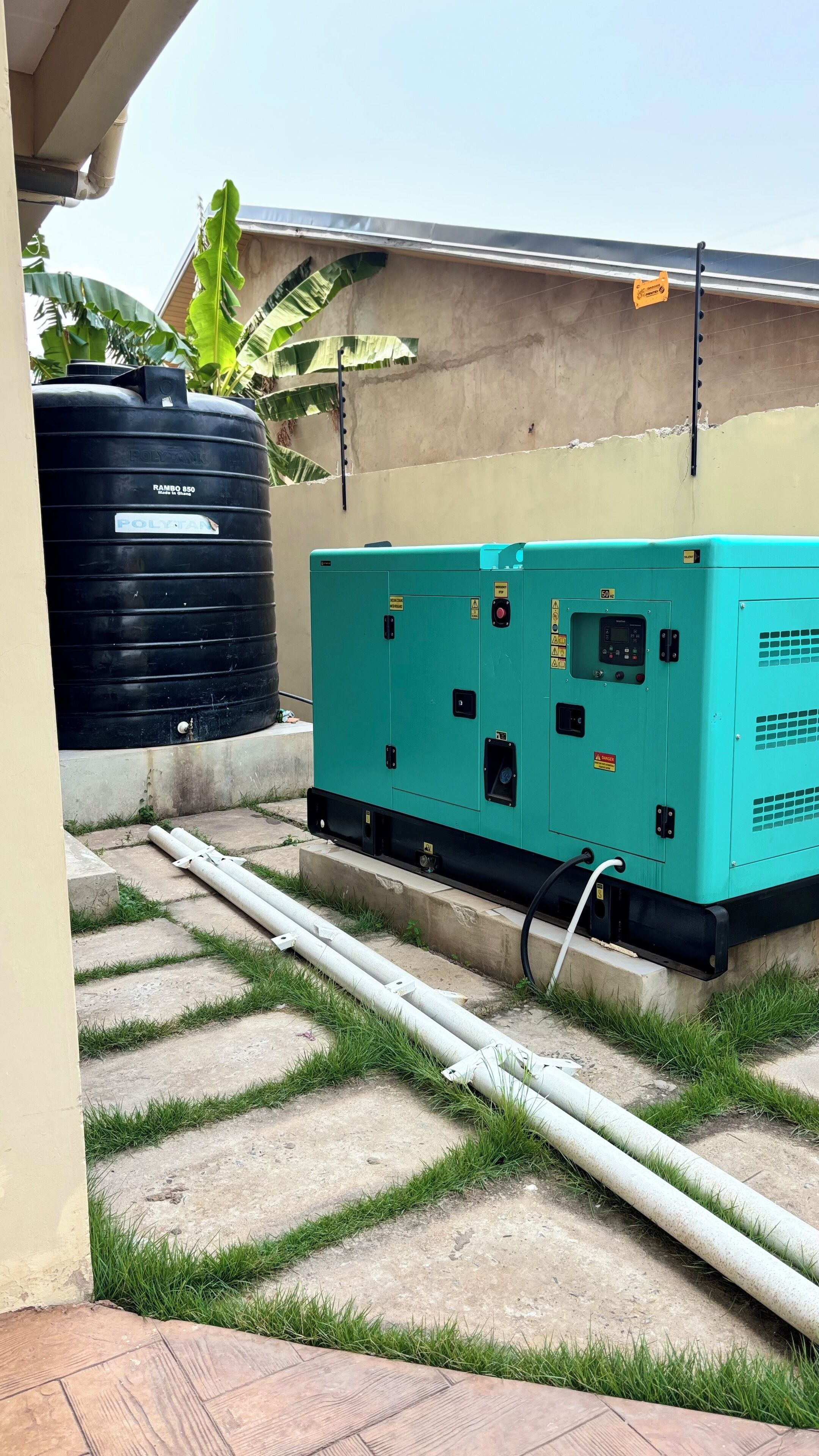 A rooftop with a large black water tank and a green electrical generator.