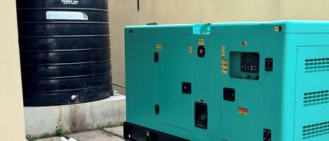 A rooftop with a large black water tank and a green electrical generator.