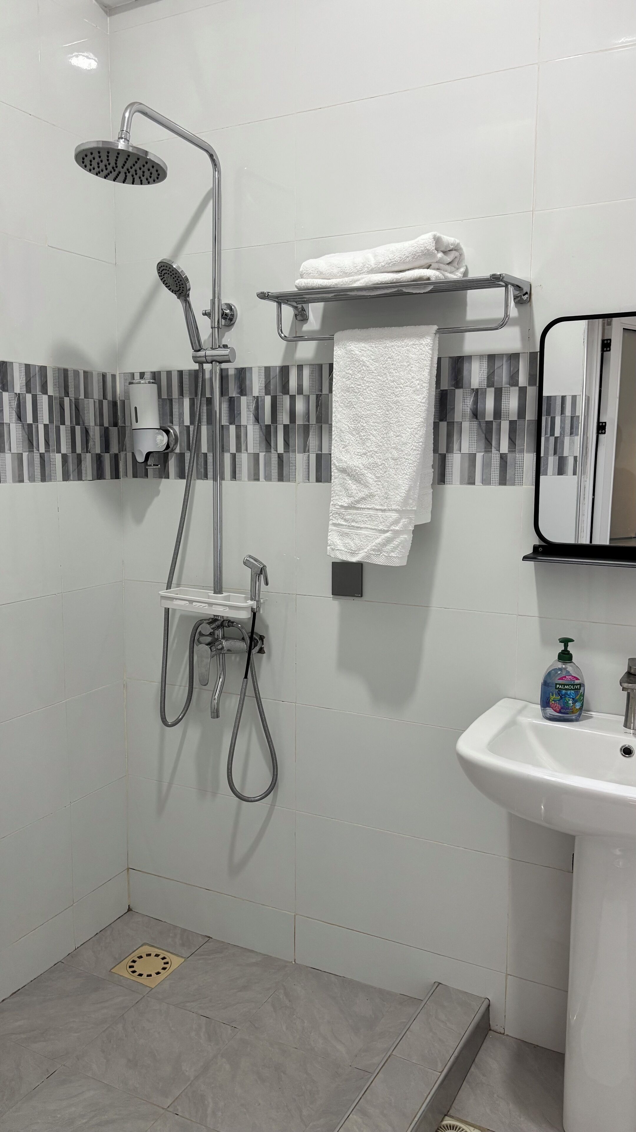 A modern bathroom with a shower, a sink, and a towel rack.