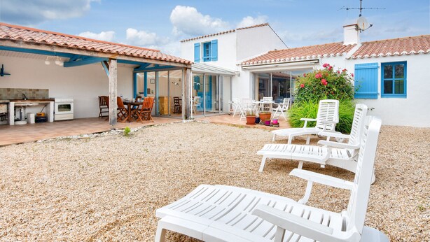 Una casa con patio, mobiliario exterior y jardín.