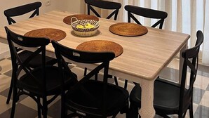 A dining area with a wooden table, black chairs, woven placemats, and a basket of fruit. - The pearl of the Sousse tourist route 5 minutes from Boujaafer beach (Sousse)