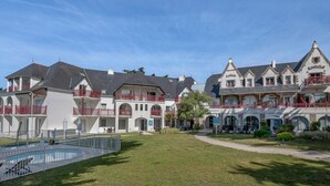 Et stort hotel med flere bygninger, swimmingpool og en velplejet græsplæne.
