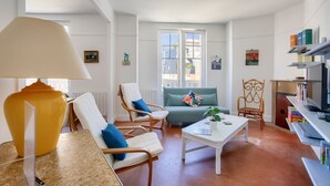 Ein Wohnzimmer mit einer Couch, Sesseln, einem Couchtisch und einer Lampe.