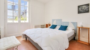 Ein Schlafzimmer mit einem großen Bett, einem Nachttisch, einem Fenster und einem an der Wand befestigten Kunstwerk.