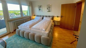 Ein Schlafzimmer mit einem großen Bett, zwei Nachttischen, einem Fenster mit Aussicht und einer Holztür.