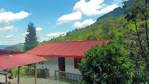 A small house with a red roof, surrounded by lush greenery and hills. - Cabañas arabi (Dosquebradas)