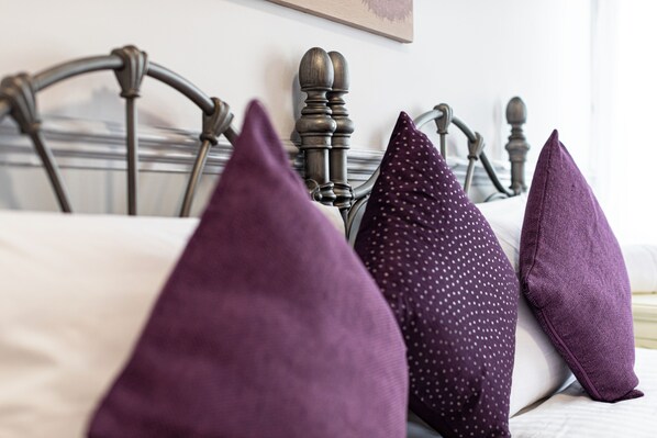 A bed with a metal headboard and multiple pillows. - The Manor Hotel (Llandudno)