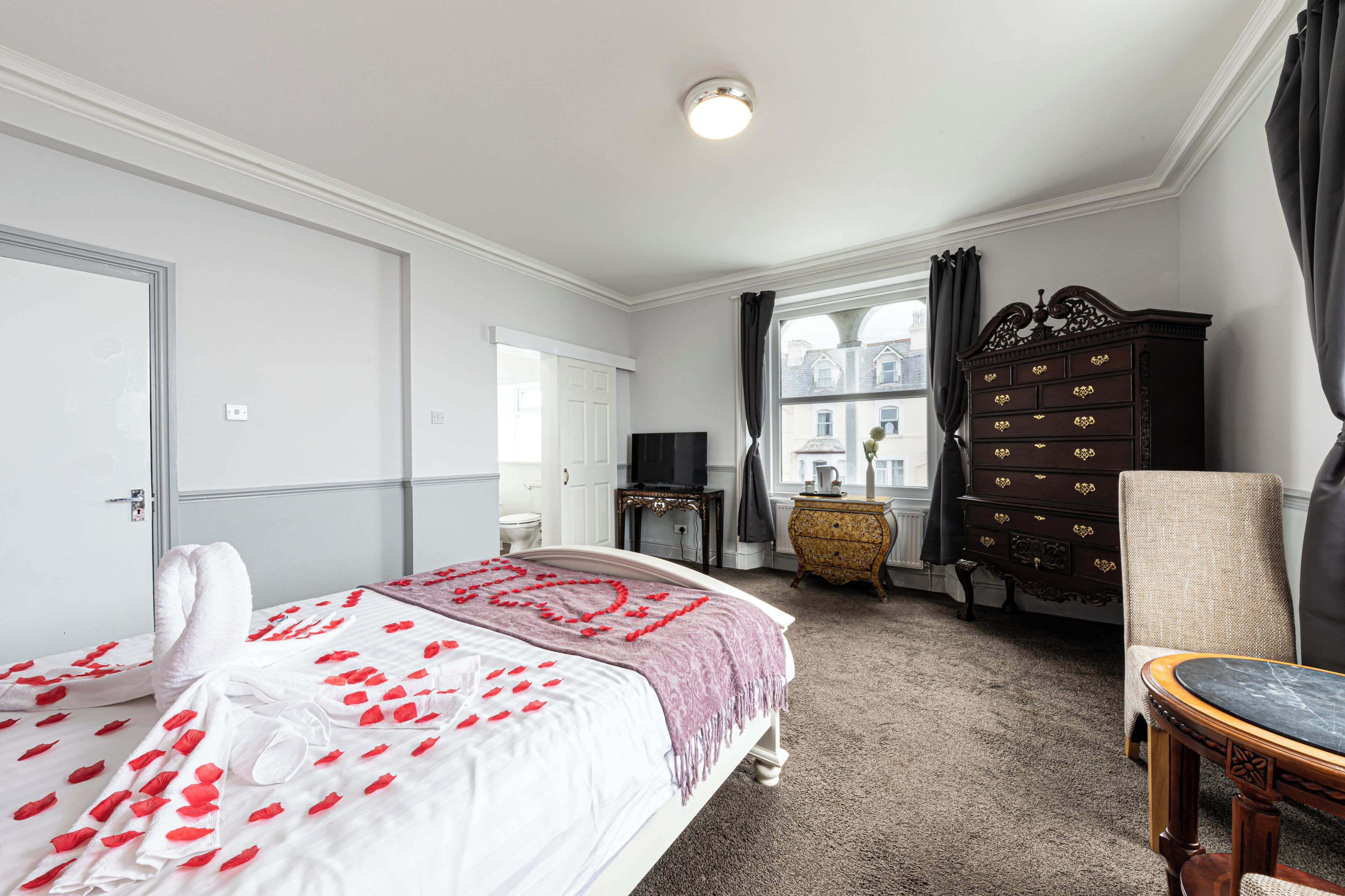 Ein Hotelzimmer mit Bett, Schminktisch, Stuhl und Fernseher.