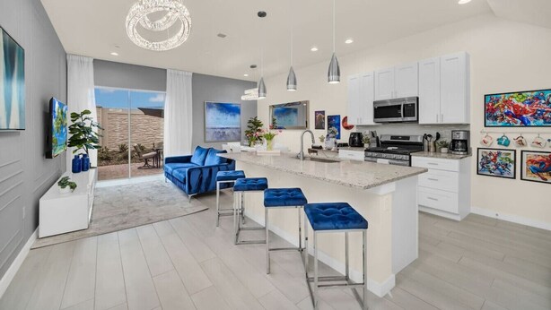 A modern kitchen with white cabinets, a central island, and bar stools. - 3BD/3BA Themed House Near Disney (Kissimmee)