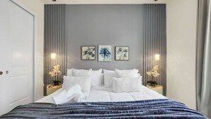 A modern bedroom with a large bed, two bedside tables with lamps, and three framed floral artworks on the wall. - 3BD/3BA Themed House Near Disney (Kissimmee)