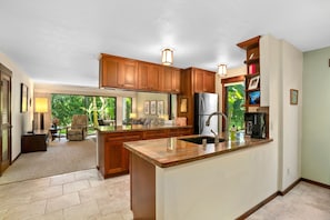 A spacious kitchen with wooden cabinets, a granite countertop, and a large island. - Kauai Waikomo Stream Villas by Coldwell Banker Island Vacations (Koloa)
