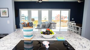 A kitchen with a black stovetop, a bowl of fruit, and a woven basket on the counter. - Hot Mess - Pool, Oceanview, Pet-Friendly Home (Emerald Isle)