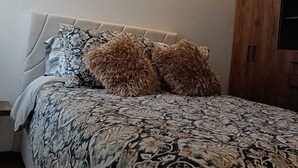 Une chambre à coucher avec un lit, une tête de lit et une armoire en bois.