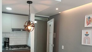 Une cuisine moderne avec des armoires blanches, une cuisinière en acier inoxydable et un luminaire suspendu.
