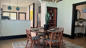 A dining area with a round table, four chairs, a patterned rug, and a potted plant.
